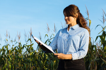 Beautiful girl agronomist with note book and analyzes the corn crop
