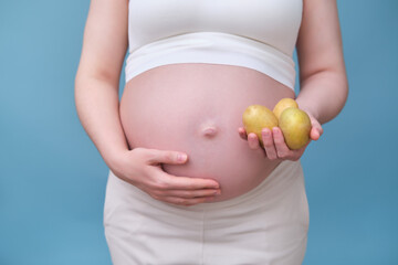 Pregnant woman with three potatoes in hand blue background