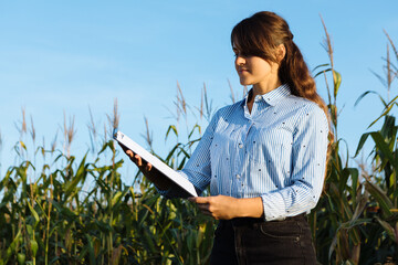 Beautiful girl agronomist with note book and analyzes the corn crop