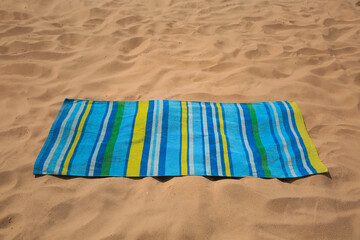 Soft bright striped beach towel on sand