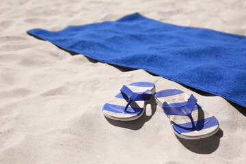 Flip flops and blue beach towel on sand