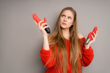 A beautiful woman with long hair chooses a dildo or a vibrator. Two massagers for sex in the hands...