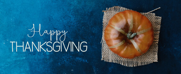 Top view of pumpkin on burlap with happy thanksgiving blue texture background.
