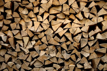 Dried beech wood ready for heating. Wooden pile in a stack. Triangular shape. Chopped firewood logs dried on a pile. Wood background texture.