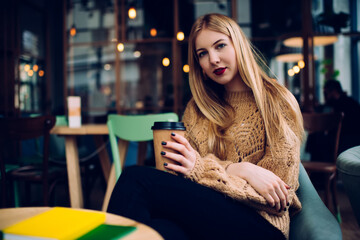 Pensive young lady drinking coffee in cafeteria