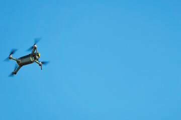 The copter flies against the background of a clear clear sky. Quadrocopter in motion. Drone flight.