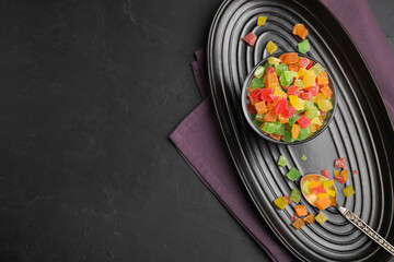 Mix of delicious candied fruits on black table, flat lay. Space for text