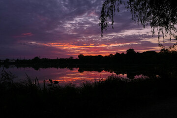 Beautiful symmetry of a dramatic sky in the water of a lake at sunset or sunrise. Stratus,...