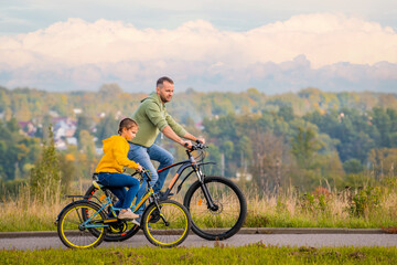 Fototapeta na wymiar Happy father and daughter take bike ride in nature in autumn.