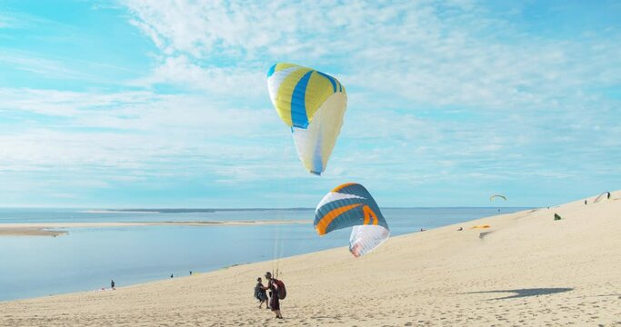 Two beach paragliders standing on the sand dunes of Pilat, practicing ground handling