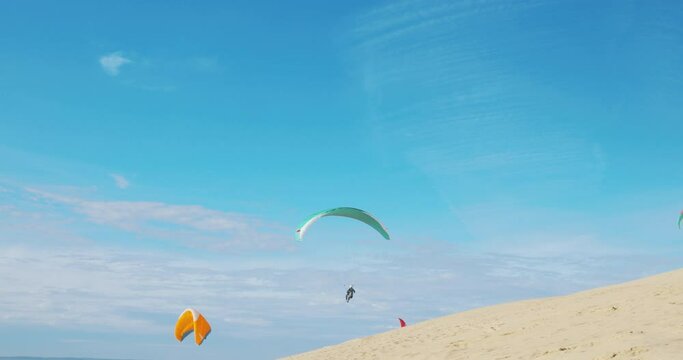 Paraglider Flying in Summer Blue Skies Over the Desert Sand Beach in France.