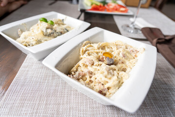 carbonare pasta in a plate with quail egg on a wooden table in a restaurant, selective focusing
