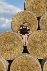 Girl posing near a stack of straw. Straw rolls, stacked in a pyramid.