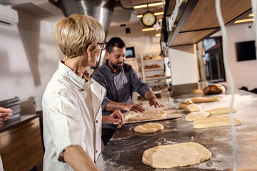 Bakers preparing dough for baking bread in modern manufacturing.