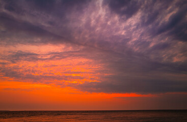 Dramatic overcast clouds, pink sunrays, and reflective ocean surface at dawn on Cape Cod in the summer