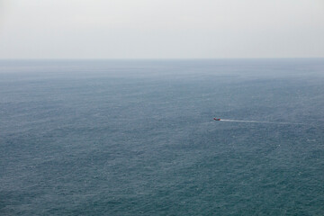 Fototapeta na wymiar Blue smooth surface of the Black Sea. Lonely sailing ship. Minimalistic landscape.