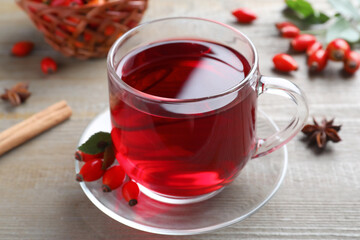 Aromatic rose hip tea and fresh berries on wooden table, closeup