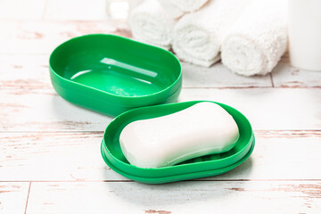 new soap on a green plastic soap dish, on a white wooden background.