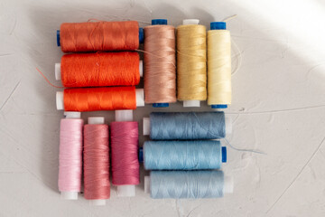 Colored cotton thread against grey background, slow fashion and home sewing concept