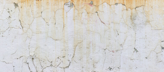 Old cracked white concrete wall with ugly yellow streaks