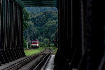 Fototapeta na wymiar Passenger train with red electric locomotive and passenger coaches in summer