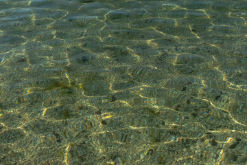 Ripples on the sea surface on a calm summer day and the reflection of sunlight in the water.