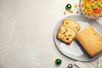 Delicious cake with candied fruits and Christmas decor on light grey marble table, flat lay. Space for text