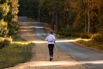 Nordic walking. A woman is engaged in Nordic walking in the park.