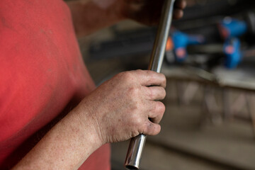 Steel pipe in hand. Small diameter of steel profile. A man holds a metal tube in the workshop.