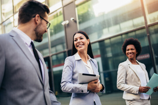 Three Young Business People Talking To Each Other While Walking Outdoors.