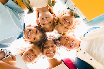 Low angle view of a group of mixed-race multi-ethnic classmates schoolchildren kids standing in...