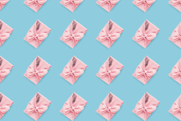 Pink gift pattern wrapping Japanese furoshiki style on light blue background, flat lay.