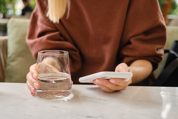 A girl is holding a modern smartphone, sending a text message or using an application on her mobile phone. Gadget addiction. Smartphone close-up. Focus on the phone screen