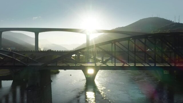 Aerial view of cars riding on bridge over Douro river in valley, Peso da Regua, Vila Real, Portugal, Europe. Drone flying over bridges in mountains. Sun shining bright in morning, 4k footage