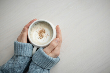 A woman in a blue sweater holding a cup of coffee, top view, cappuccino. A cup of coffee. white background. High quality photo