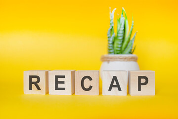 RECAP word written on wood block. yellow background, concept