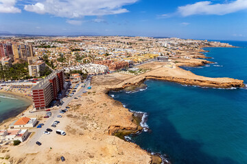 Aerial panoramic drone point of view rocky coastline of spanish tourist resort town of Torrevieja during sunny summer day. Province of Alicante, south of Spain, Costa Blanca. Spain. Travel and tourism