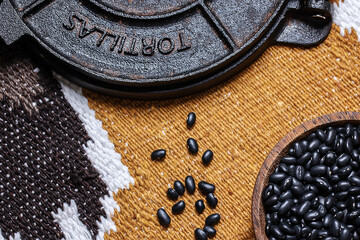 Iron tortilla press and black beans on Mexican carpet