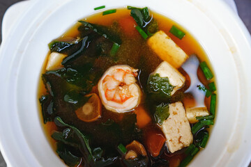 soup with shrimp, algae, mushrooms and tofu cheese in a white plate. top view.