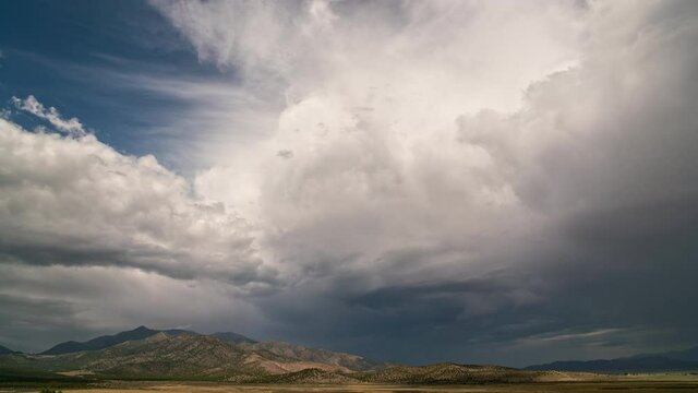 Time-lapse of clouds moving over landscape in Utah with Flat Top Mountain in the distance by Cedar Valley.