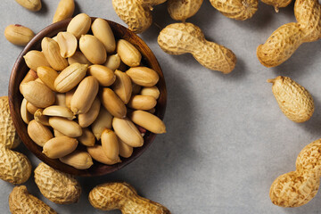 Peanuts in wooden bamboo bowl on concrete background. Nuts.