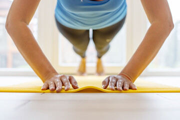 Young sports woman in sportswear on a yoga mat doing push ups or pushing exercises. Weight loss, healthy lifestyle concept