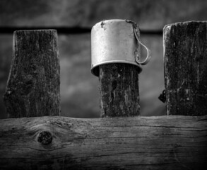 A mug on the fence. Rustic still life. Black and white.