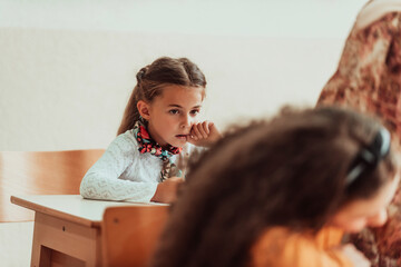 The girl sitting confusedly in the school desk and attends classes. Selective focus