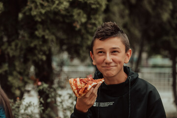 A boy eats pizza on a lunch break at school. Selective focus