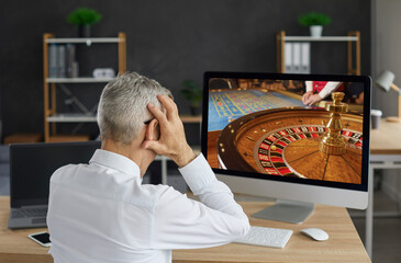Unlucky old gambler places bet in online casino gambling game and loses all his money. Back view of...