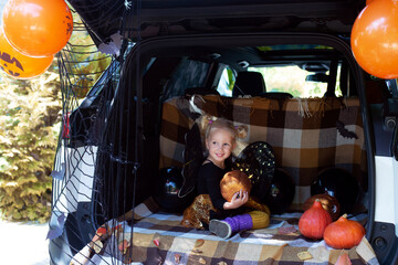 Little girl celebrating Halloween car trunk. Stay home. Autumn holidays.