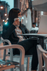 Mujer joven empresaria con mascarilla cansada tomando café en una cafeteria de la capital por la...