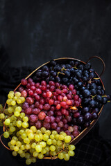White, red and black fresh autumn grapes on dark background, top view