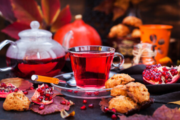 Glass cup of hot red tea and fresh homemade delicious apple cookies on rustic autumn background